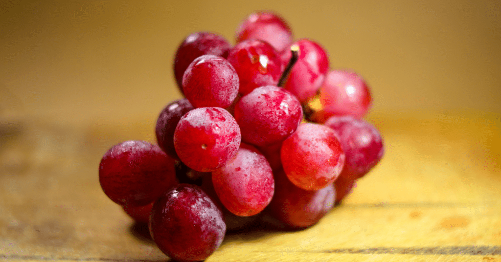 Red grapes sitting on a wooden table